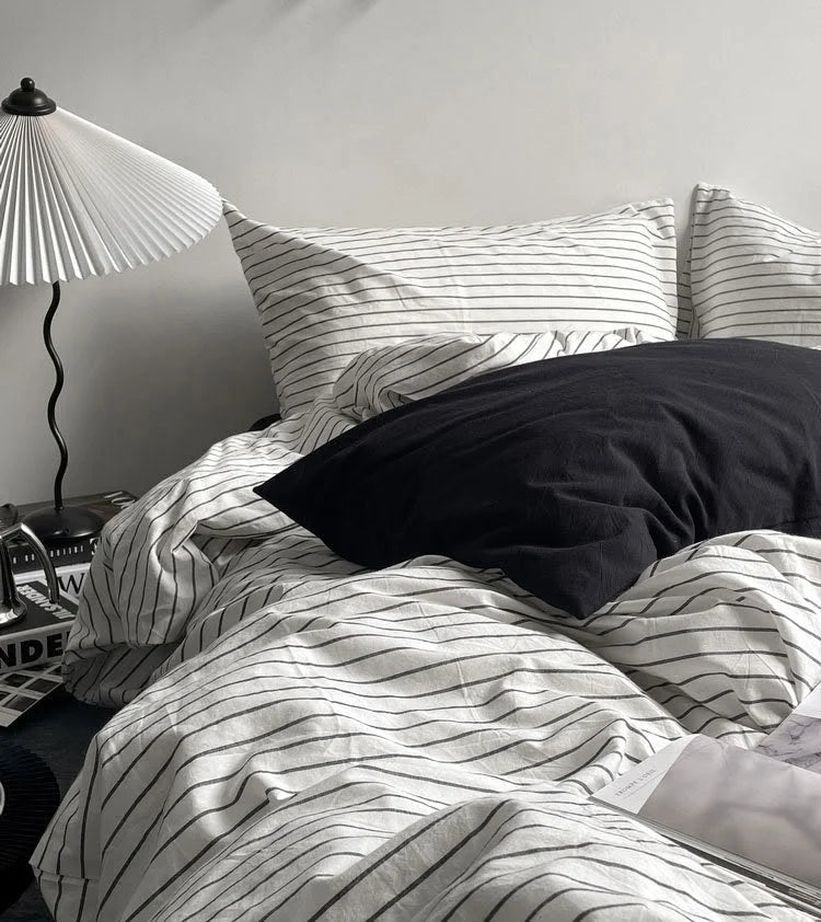 Close-up of the pinstripe washed cotton pillowcases and a solid black pillow, showing the soft fabric texture. - RoomDen