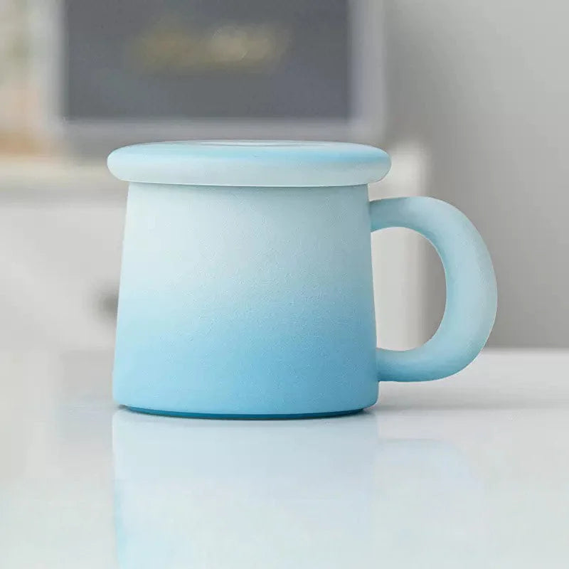 Side view of the Sky Blue Ombre Frosted Ceramic Mug with lid on a white surface - RoomDen.