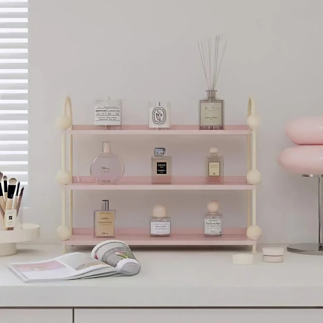 Pastel Pink & Cream version of the 3-tier desk organizer holding perfume bottles on a white desk - RoomDen.