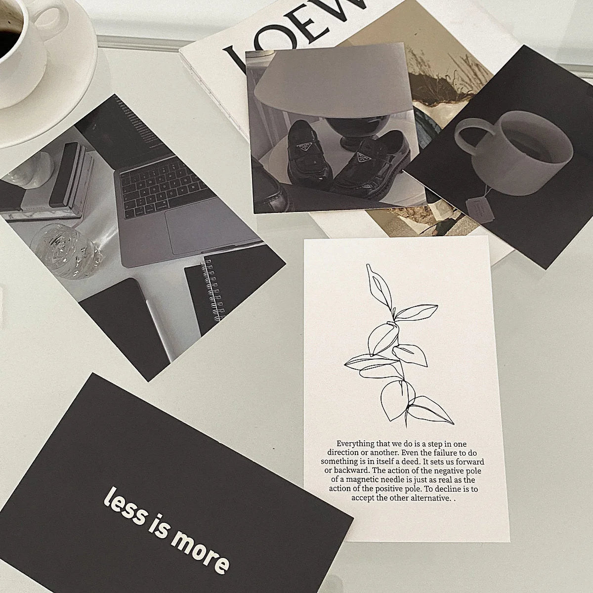 Flatlay of the Dark Academia-themed wall collage kit cards scattered on a white desk with a coffee cup and magazines. - RoomDen