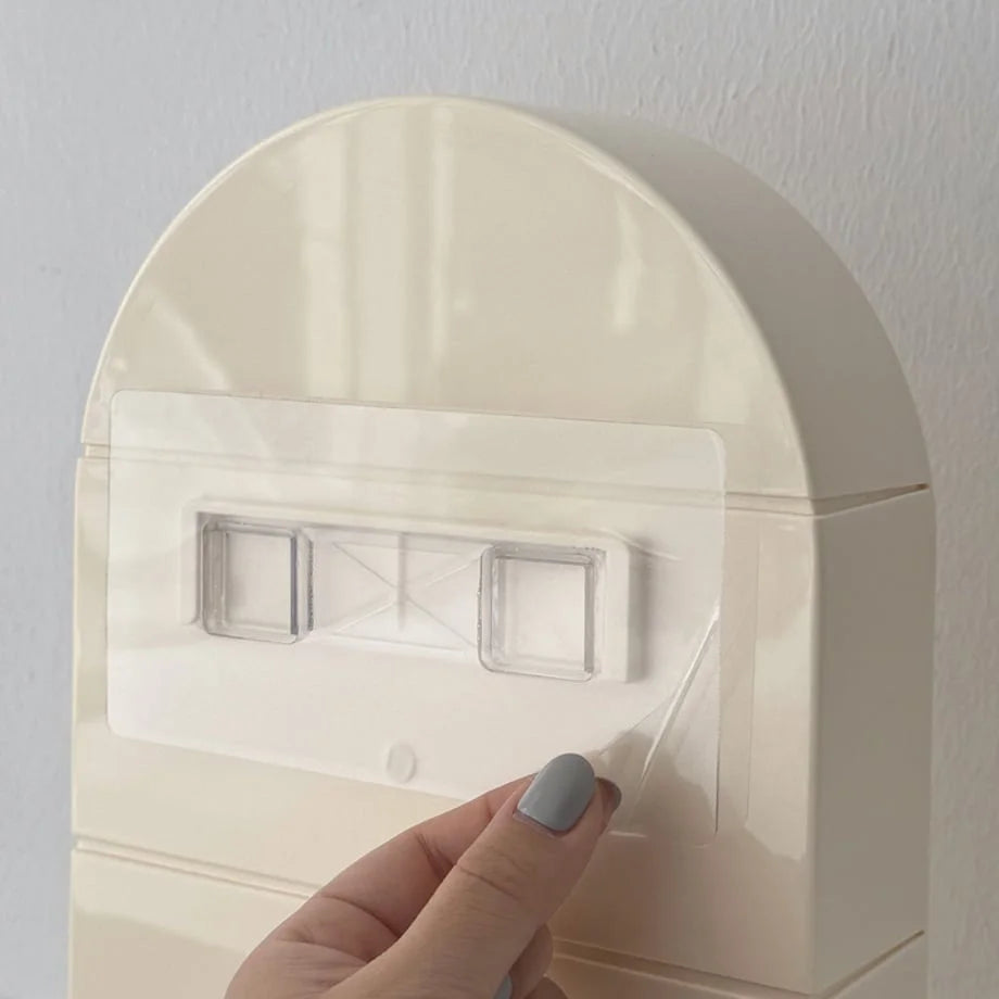 A hand applying the transparent adhesive mount to the back of the cream arched shelf - RoomDen.