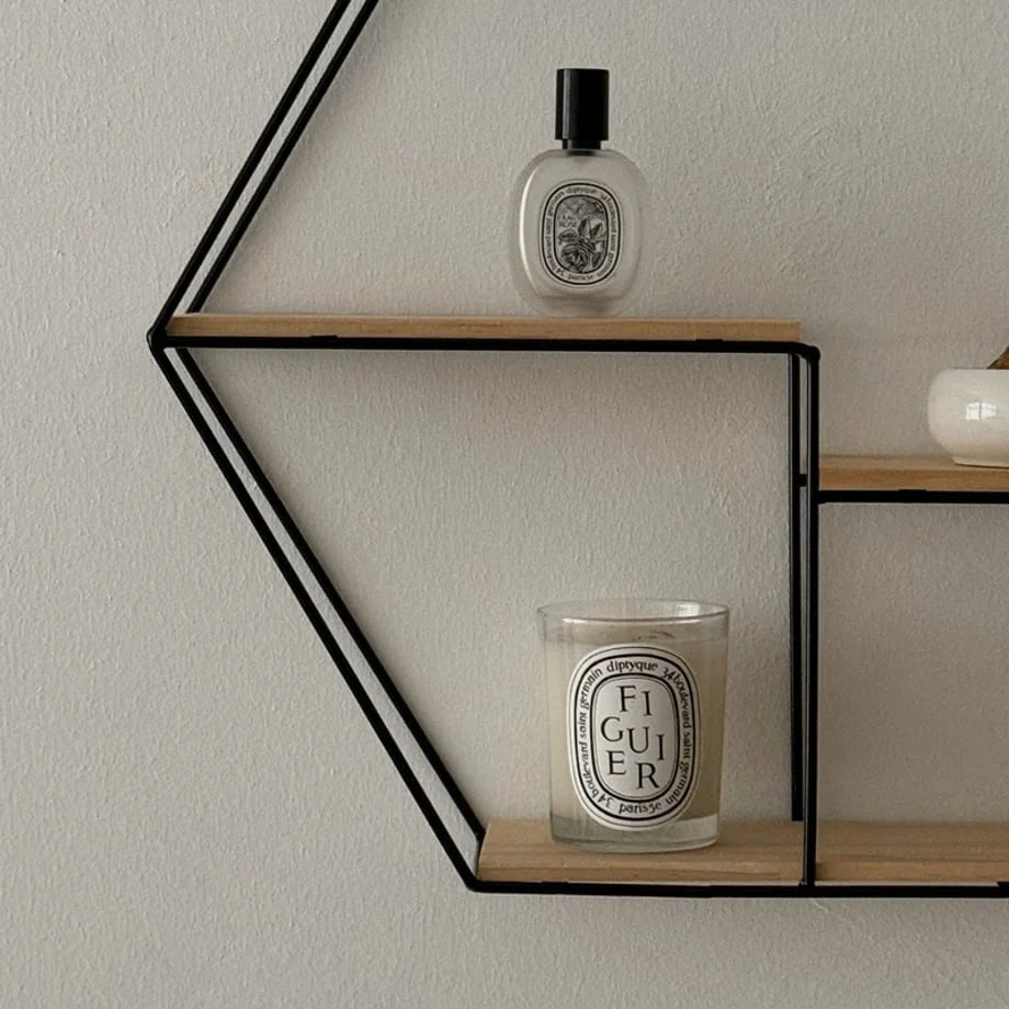 Close-up showing a candle and perfume bottle on the Black Hexagon Wall Shelf - RoomDen