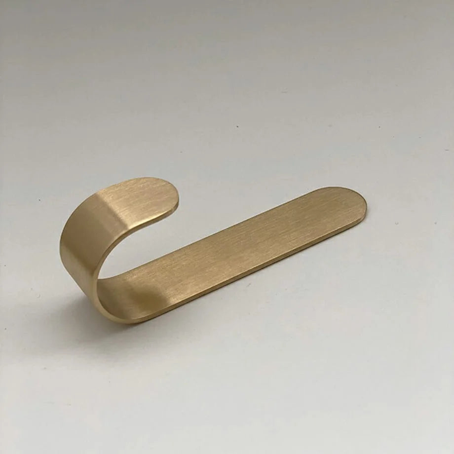 A single brushed gold metal J-shape decorative hook shown on a plain white background, highlighting its sleek, minimalist design - RoomDen