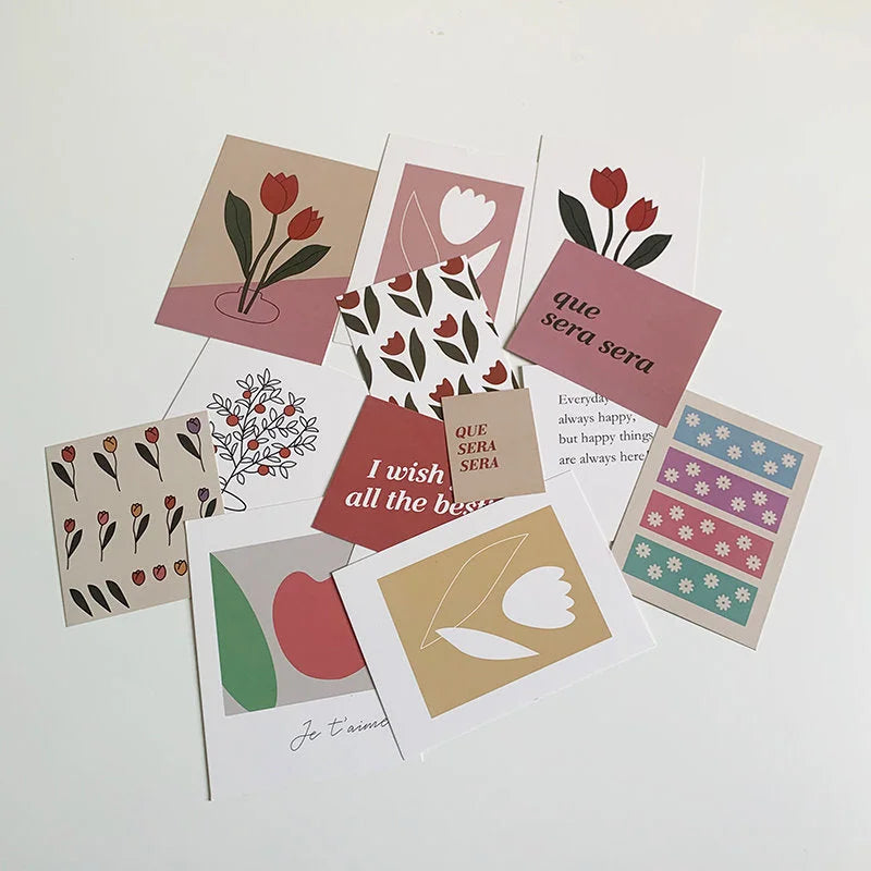 A scattered pile of the 15 assorted art prints from the wall collage kit, showing various designs. - RoomDen