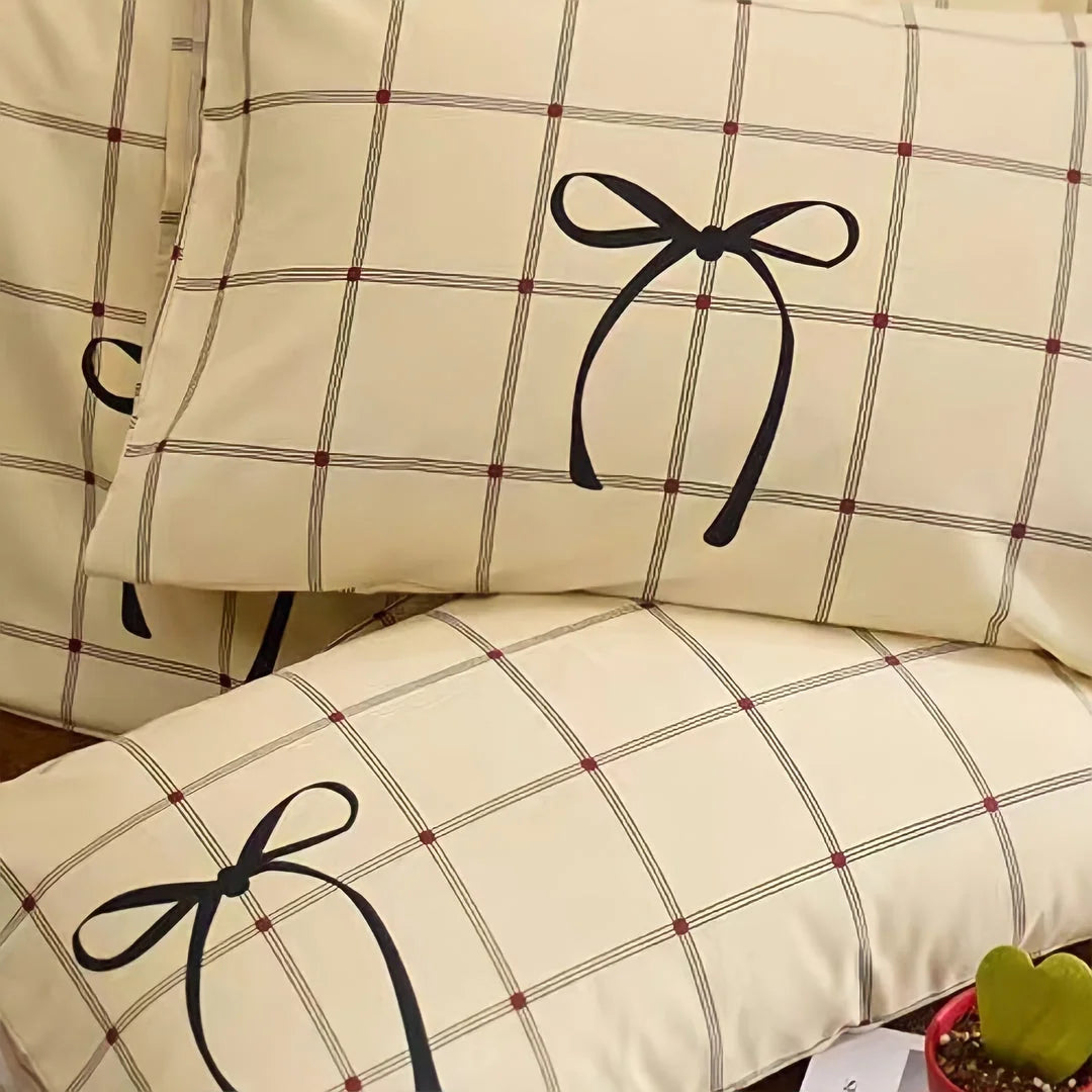 Close-up detail of the black bow print and red-dotted grid on the cotton pillowcases. - RoomDen