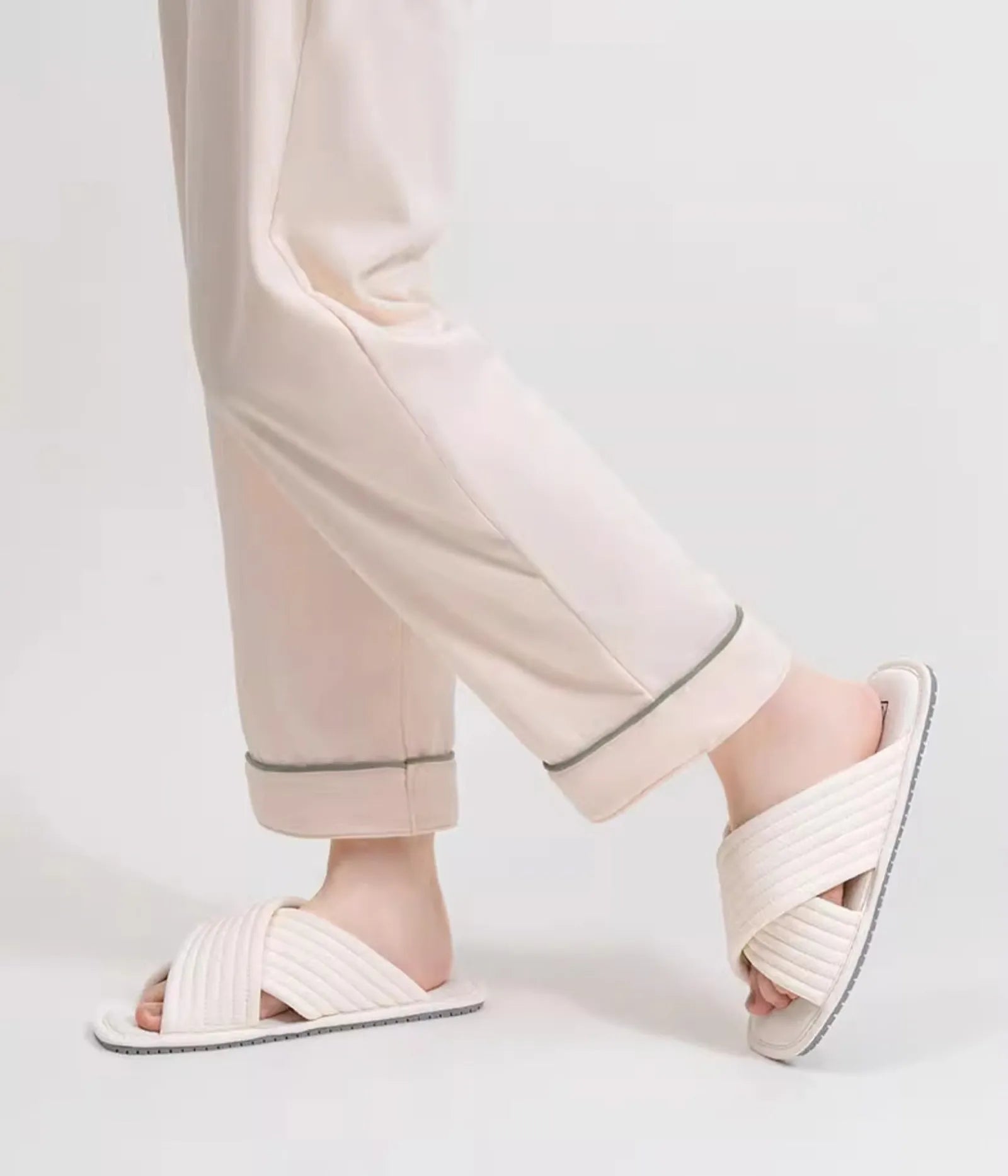 Cream beige cotton cross-strap slippers worn on feet side view