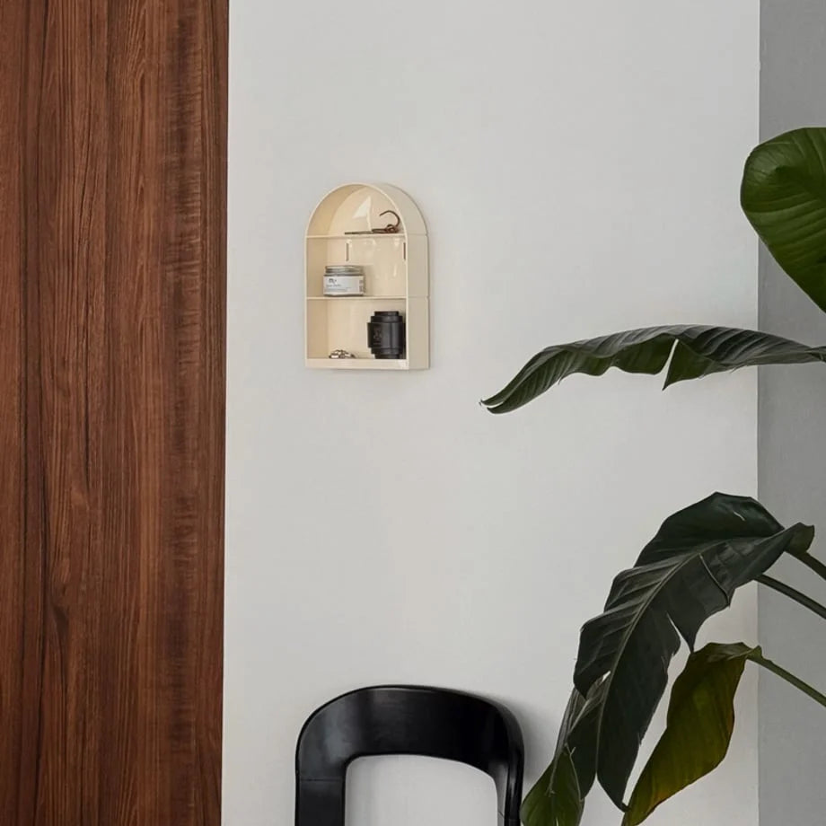Wide shot of the cream arched wall shelf in a room with a large plant and black chair - RoomDen.