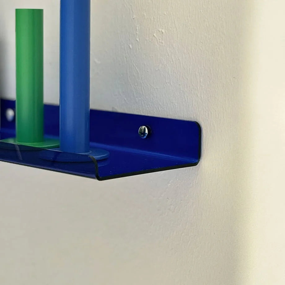 Close-up detail of the blue acrylic shelf's sleek curved edge and silver mounting screw against a textured white wall.