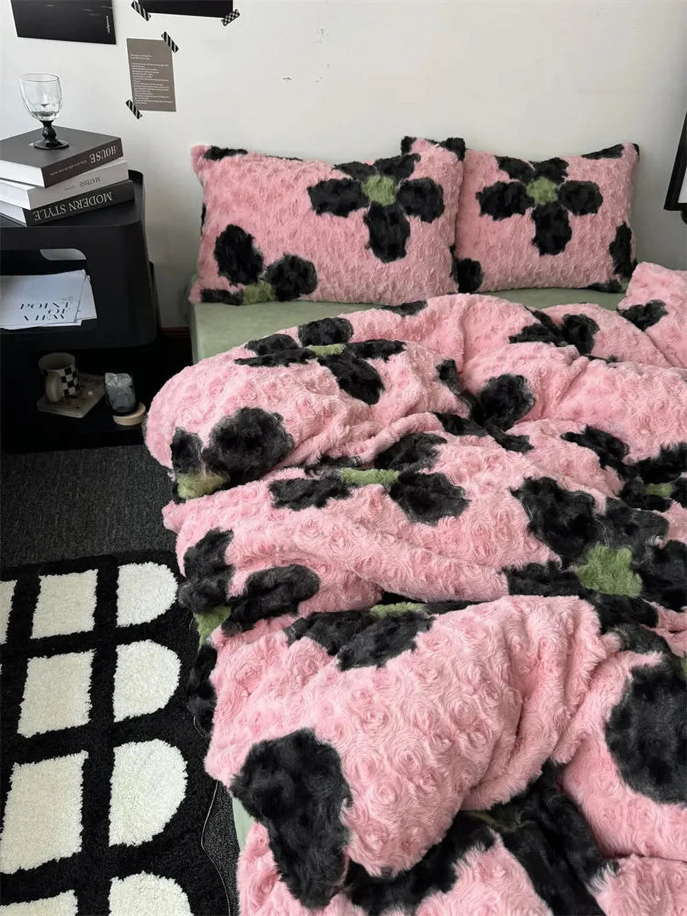 Close-up lifestyle shot of the plush pink and black abstract floral fleece bedding set on a bed. - RoomDen
