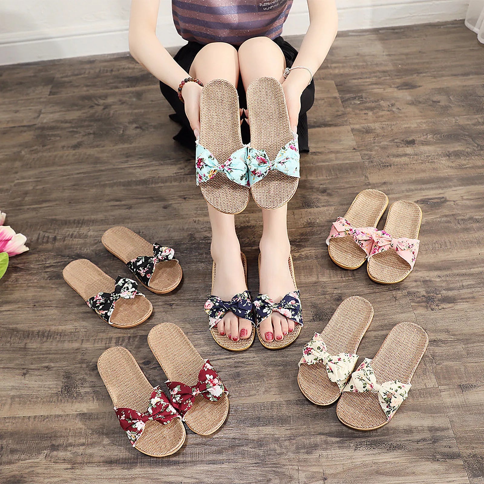 Woman holding Aqua Floral slippers with color variations displayed on floor - RoomDen