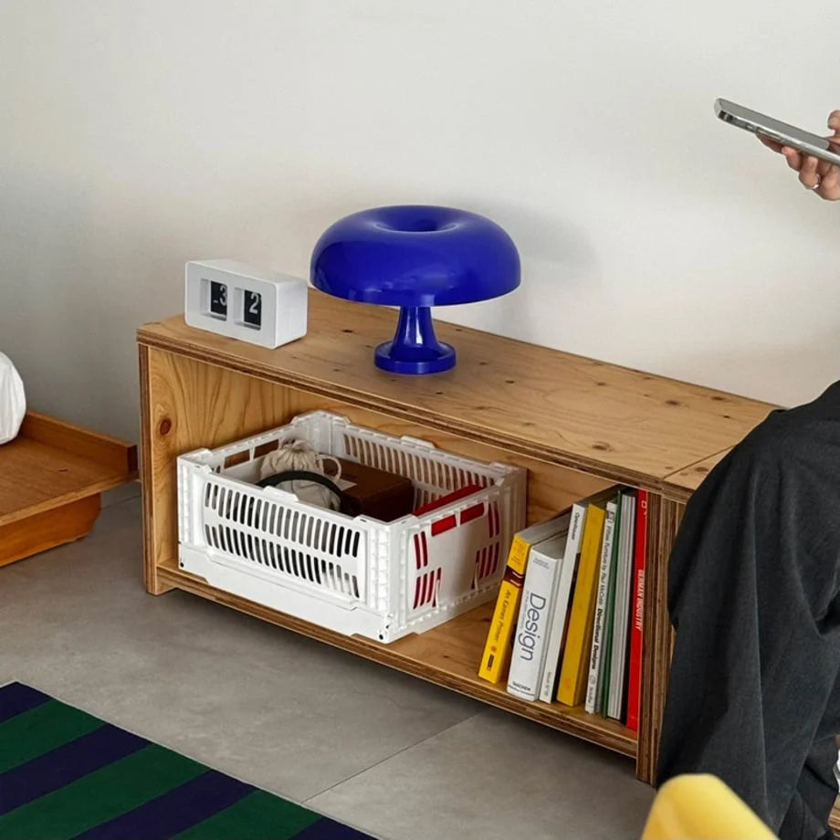 A modern room scene with a cobalt blue mushroom lamp on a wooden shelf with books - RoomDen.
