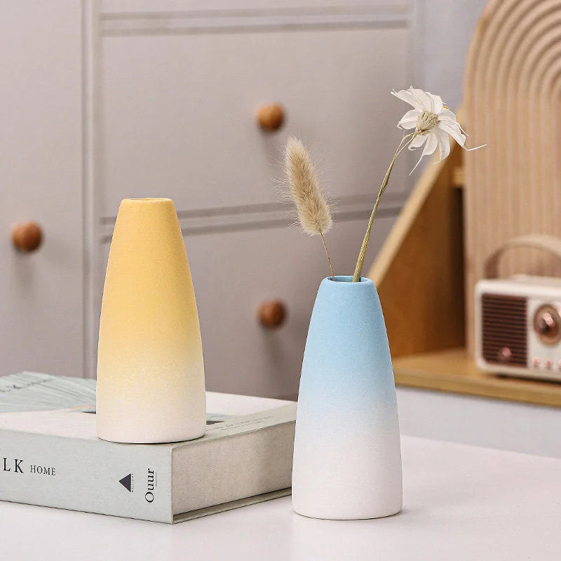 Yellow cone and blue gourd shaped ombre ceramic vases displayed on a book - RoomDen.