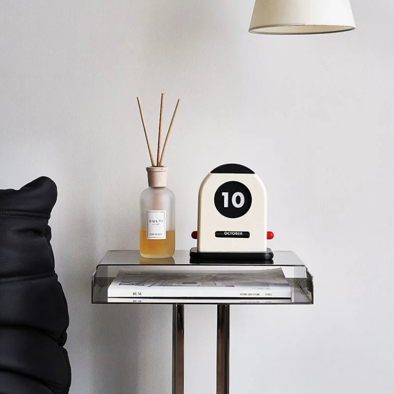 The wooden desk calendar on a clear acrylic side table next to a reed diffuser - RoomDen