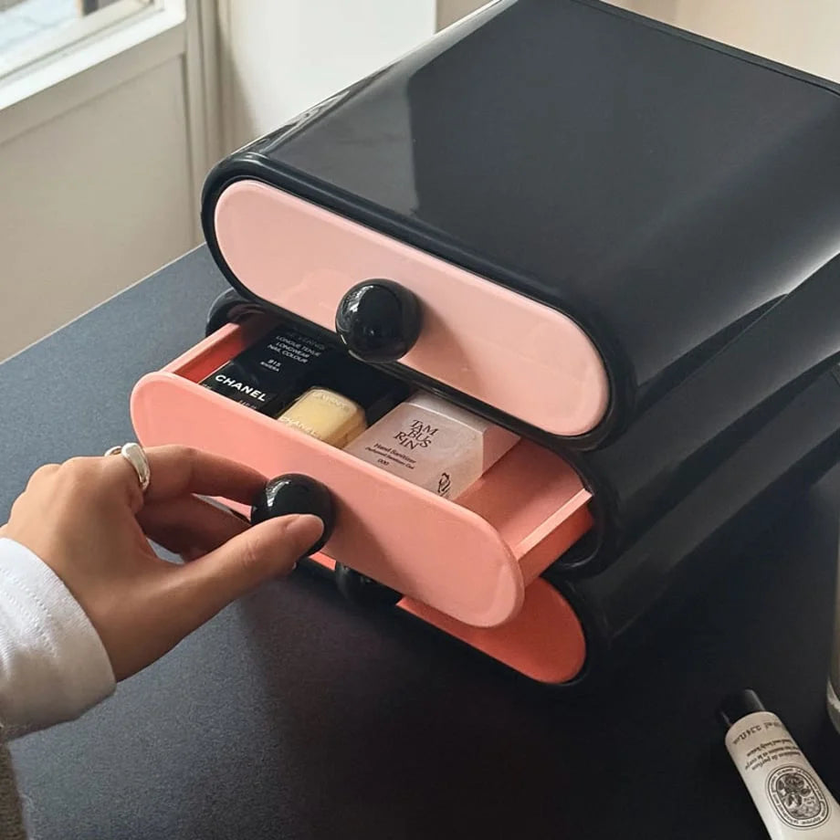 Hand opening the middle pink drawer of the wavy makeup organizer, showing stored cosmetics. - RoomDen