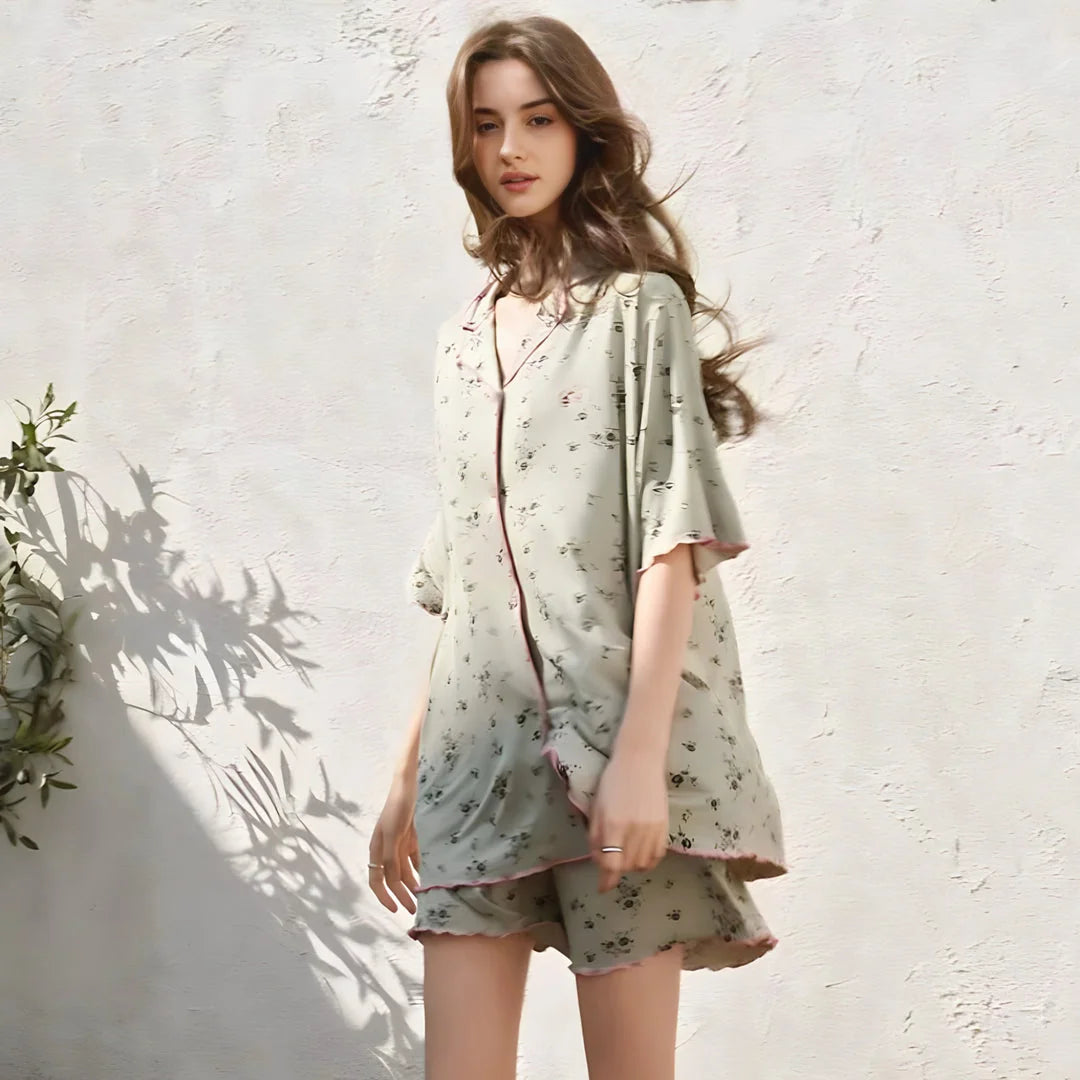 Model looking at the camera, wearing the ditsy floral pajama set with pink trim, with a gentle breeze in her hair. - RoomDen