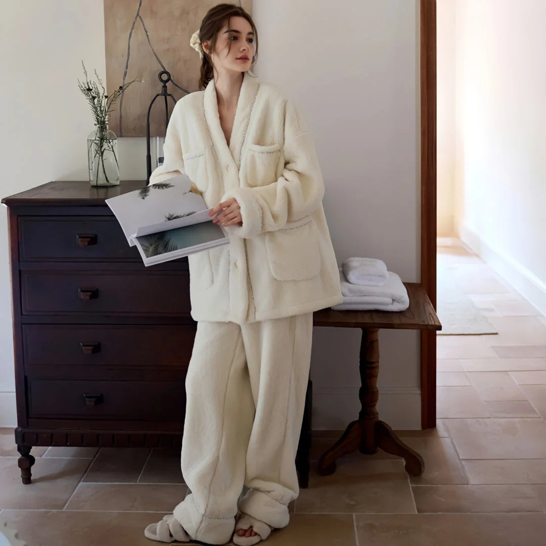 Model wearing the plush cream flannel fleece pajama set, standing next to a dark wood dresser and holding a magazine - RoomDen.