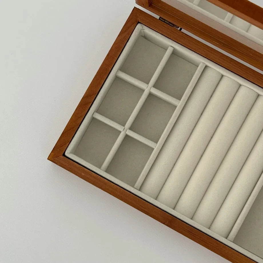 A detailed view of the empty, beige-lined interior compartments of the wood jewelry organizer.
