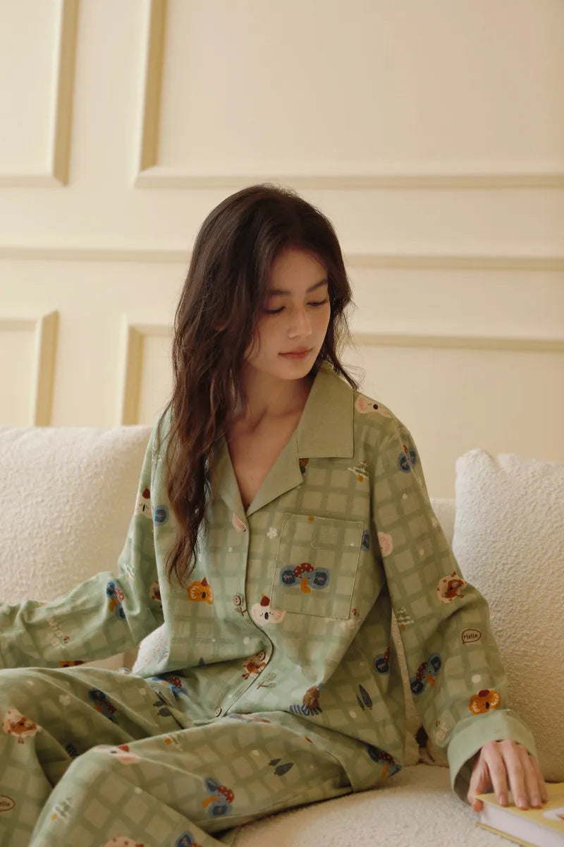 Woman sitting on sofa looking down wearing sage green kawaii style pajama set