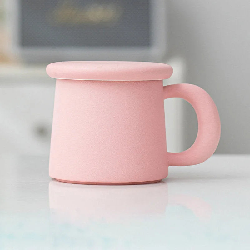Side view of the solid Dusty Pink Frosted Ceramic Mug with lid on a white surface - RoomDen.