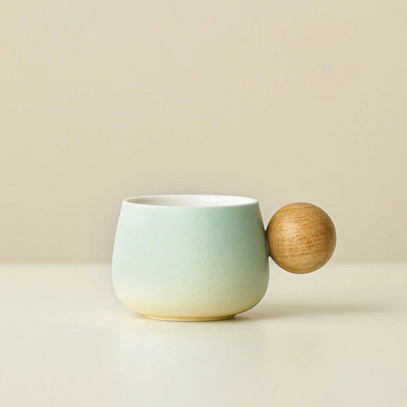 A clear studio shot of the Mint Green gradient ceramic mug with its spherical wooden handle. - RoomDen