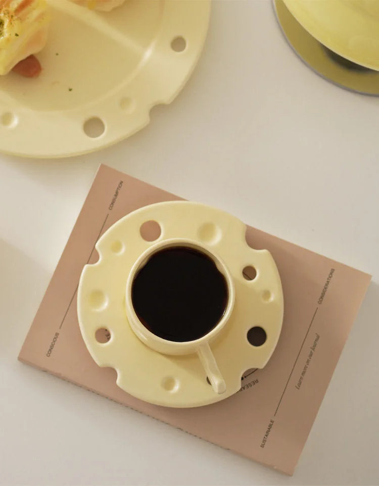 Top view of the yellow Cheese Ceramic Mug filled with black coffee, sitting on its matching saucer. - RoomDen