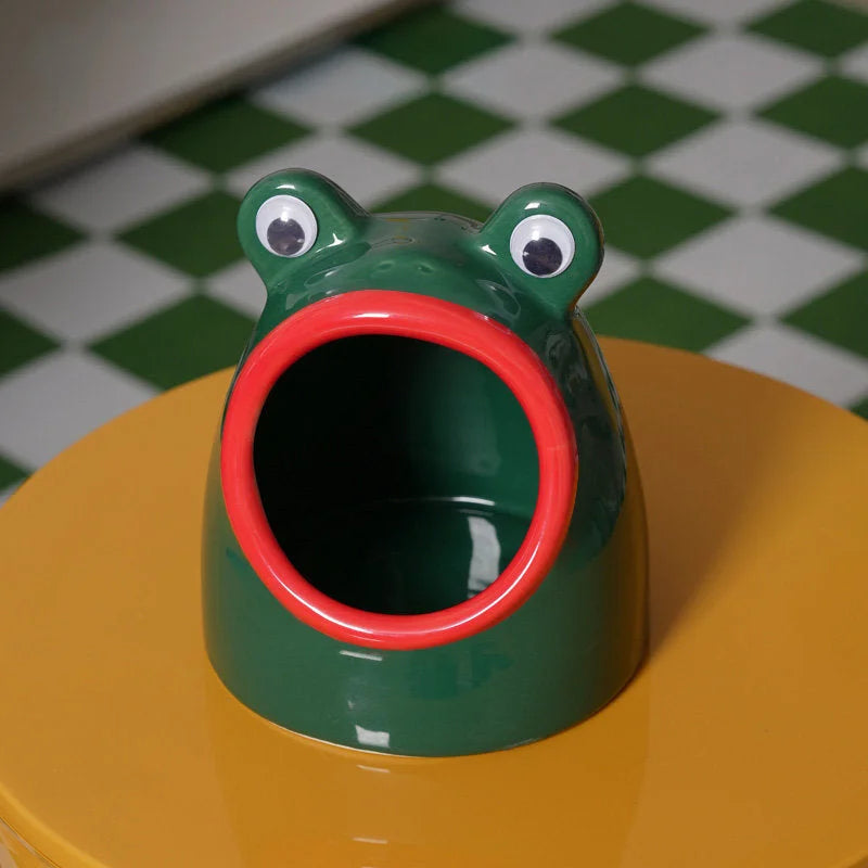 Front view of the green and red ceramic frog organizer on a yellow table with a green and white checkered floor. - RoomDen