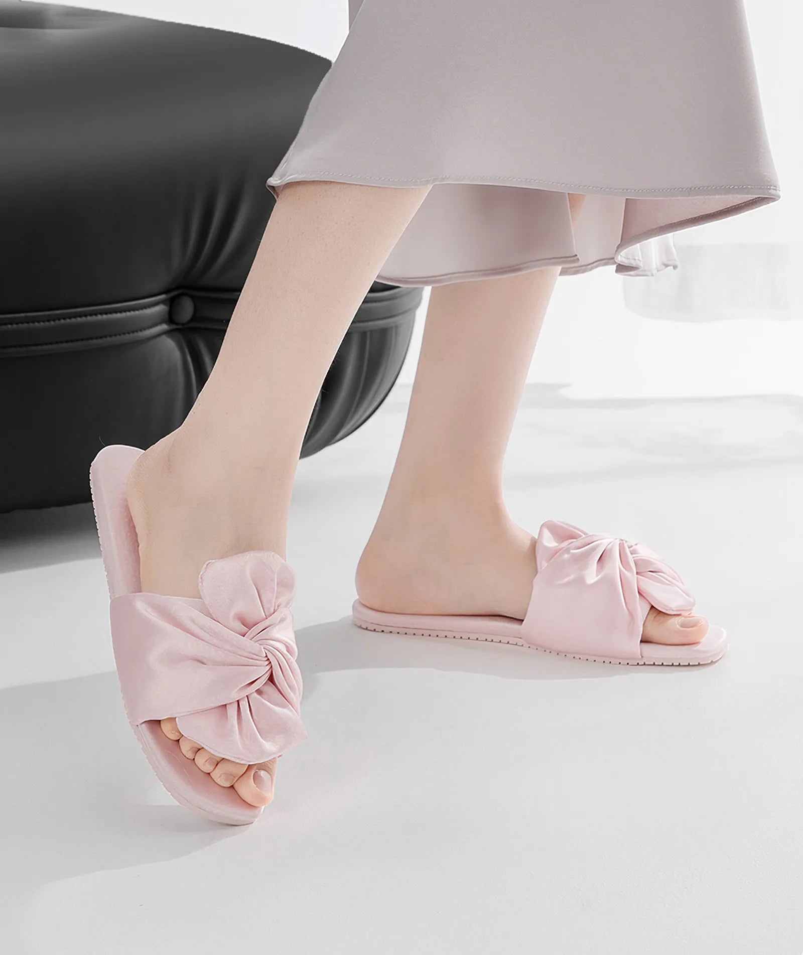RoomDen Silky Ruched Bow Cotton Sateen House Slippers in Blush Pink styled with ottoman