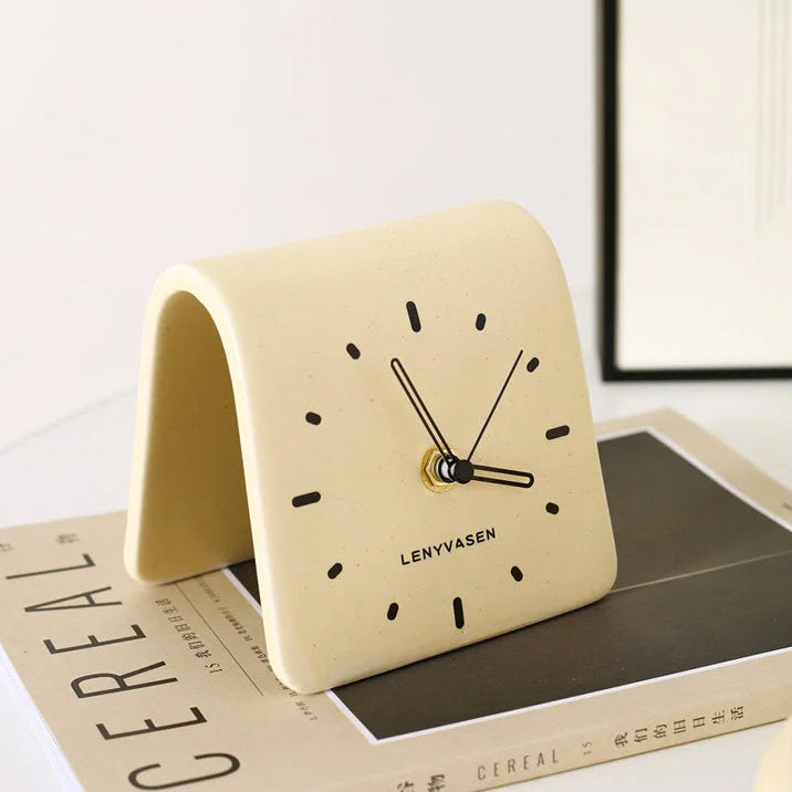Lifestyle image of the Butter Yellow Matte Arch Ceramic Table Clock on a CEREAL magazine - RoomDen