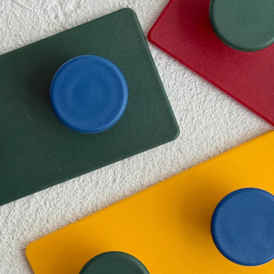 Top-down angle of the red, green, and yellow Colorblock Decorative Hooks, highlighting the minimalist design - RoomDen.