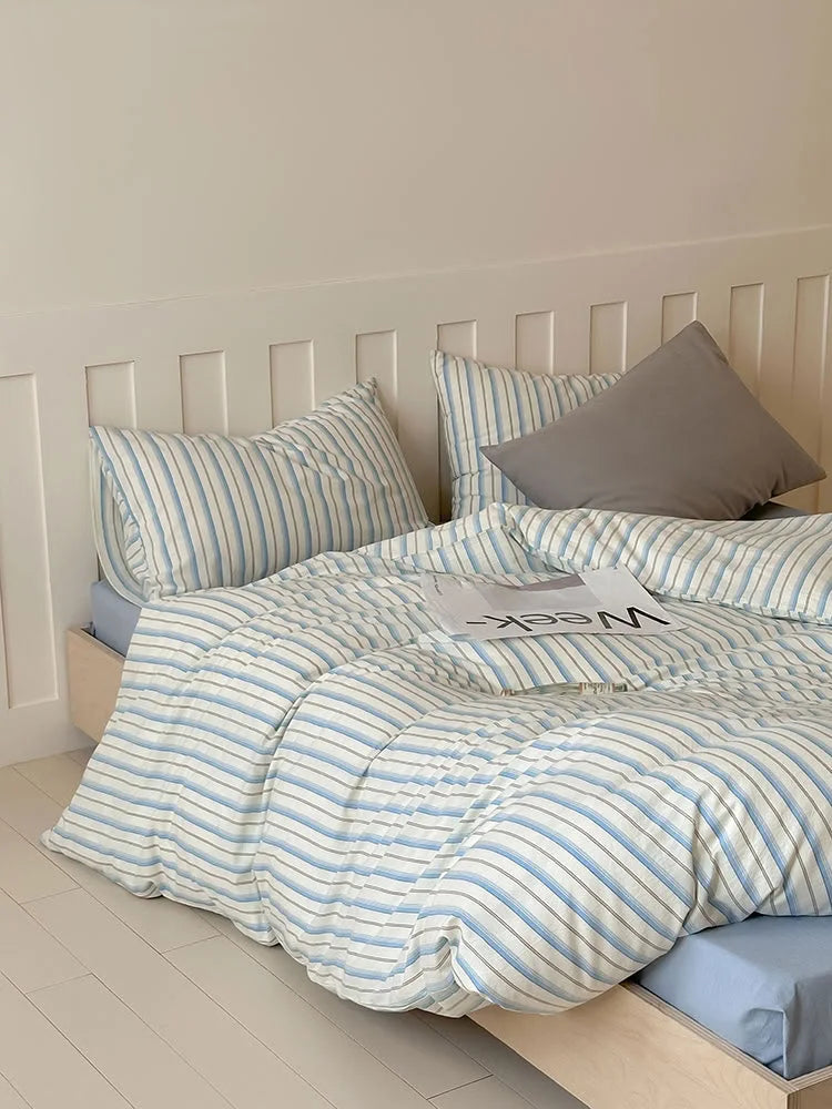 The Blue Striped variant of the Textured Pinstripe Washed Cotton Bedding Set on a bed with a blue sheet. - RoomDen