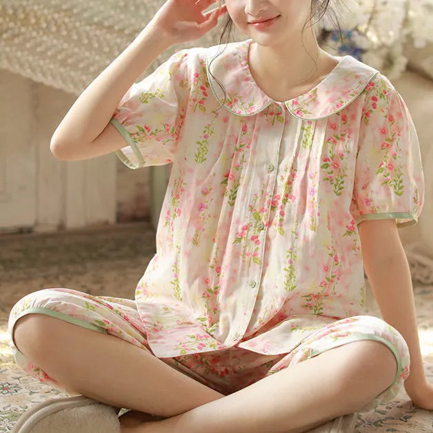 Model sitting cross-legged on floor showcasing breathable washed cotton pajama shorts and top - RoomDen