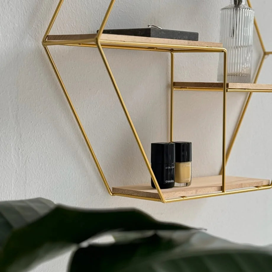 Close-up of the Gold Hexagon Wall Shelf's lower tier holding nail polish bottles - RoomDen