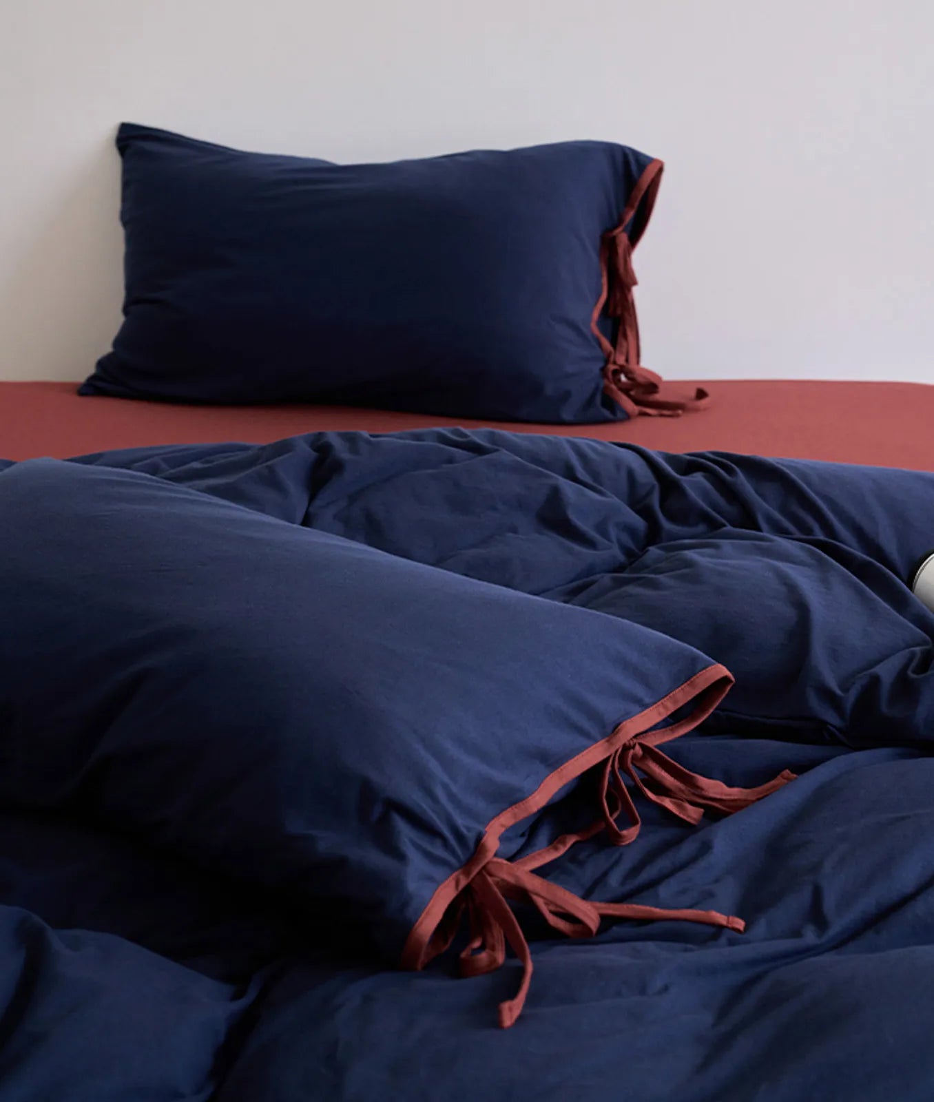 Navy & Terracotta variant of the Contrast Tie Washed Cotton Bedding Set on a bed. - RoomDen