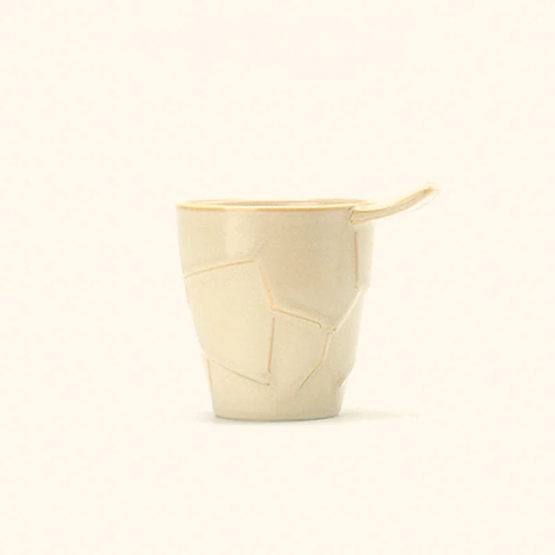 A Cream White Textured Geometric Ceramic Coffee Cup with its unique fin handle, studio shot - RoomDen