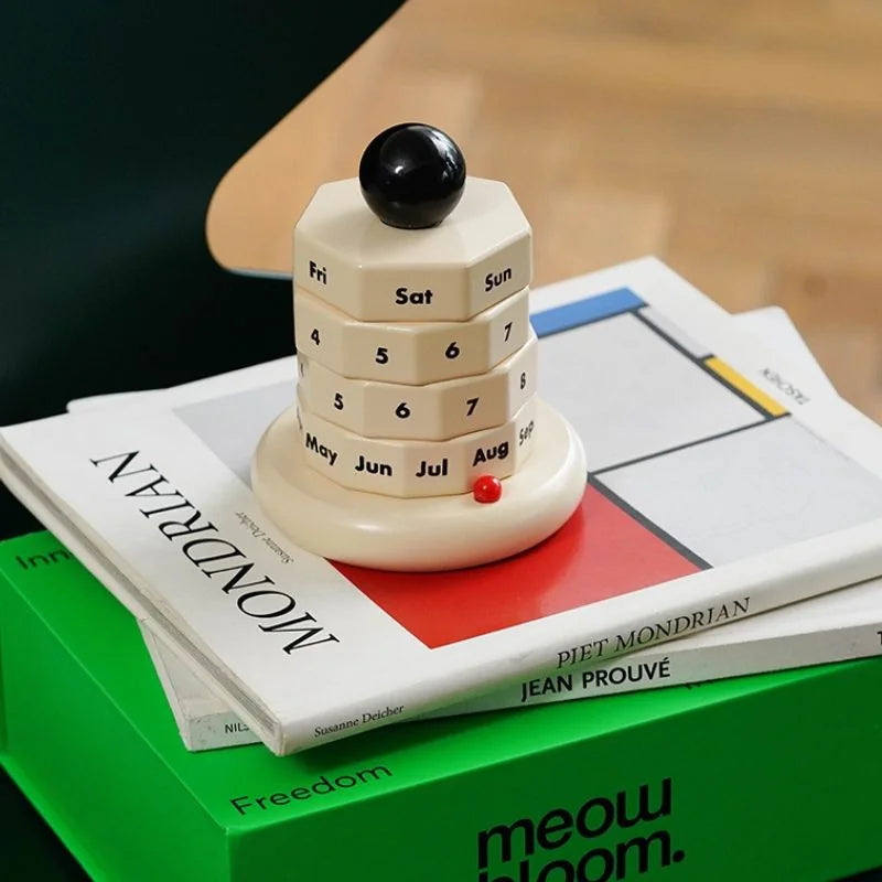 Close-up of the minimalist perpetual calendar on a stack of books, including "MONDRIAN". - RoomDen
