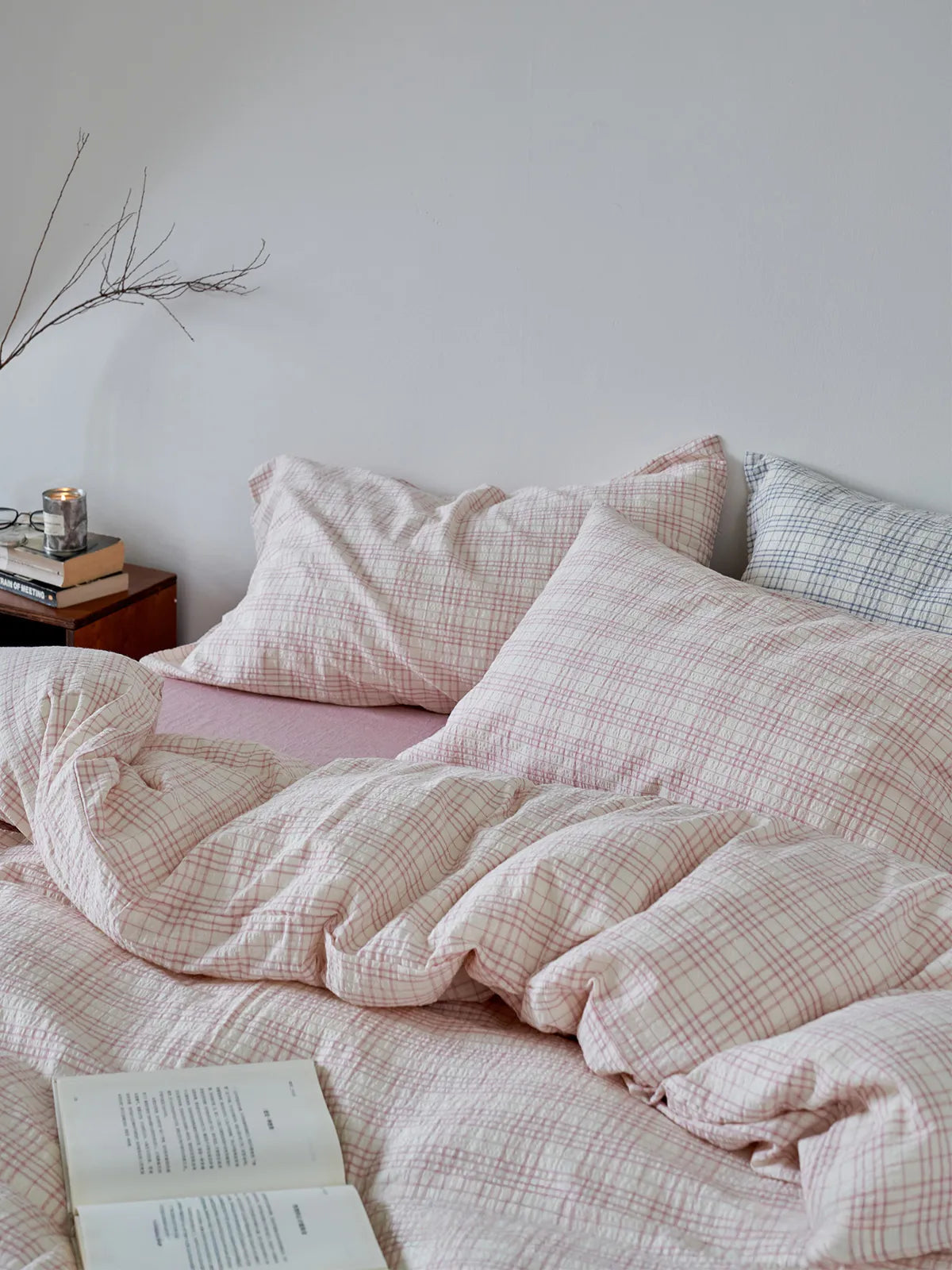 Close-up of the wrinkled texture of the Dusty Pink Plaid Washed Cotton Bedding Set with an open book - RoomDen