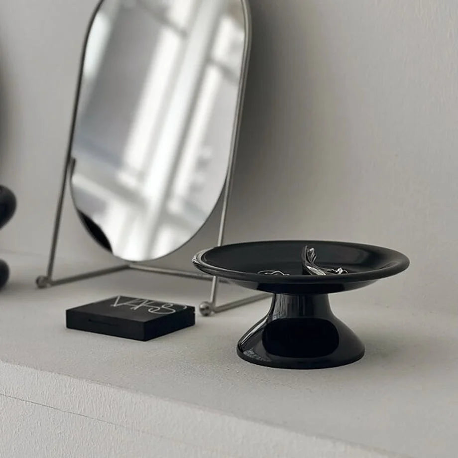 Angled view of the black trinket tray, showing its glossy finish and reflection of a mirror. - RoomDen