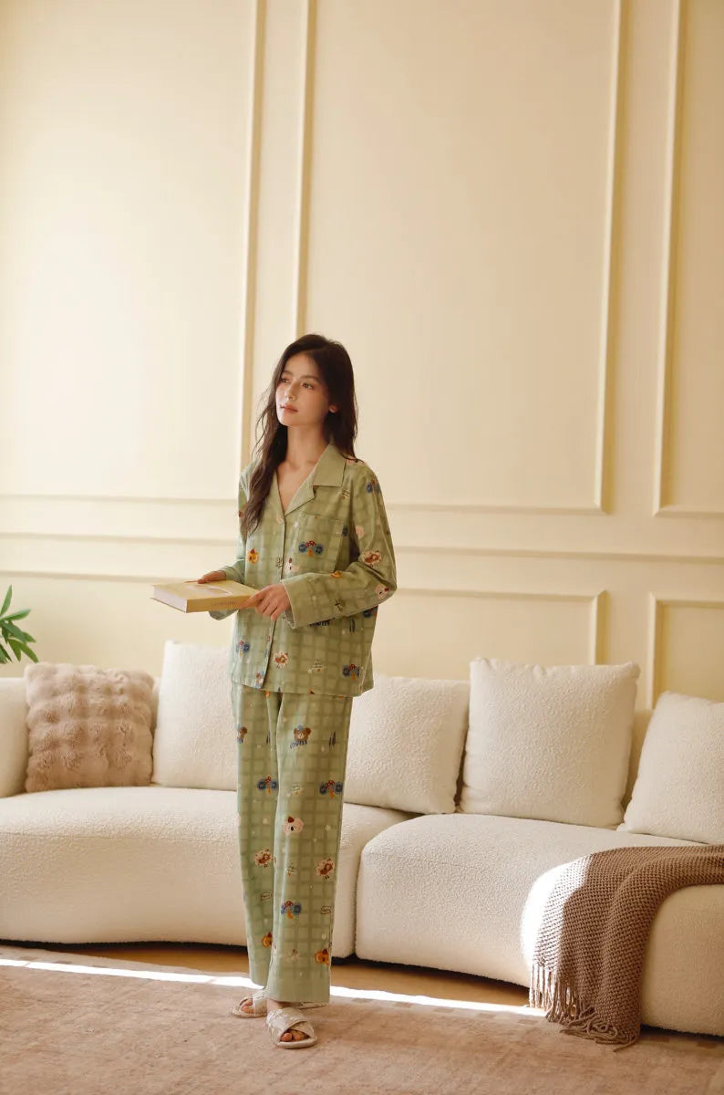 Full body standing view of woman wearing sage green washed cotton pajama set in cozy room