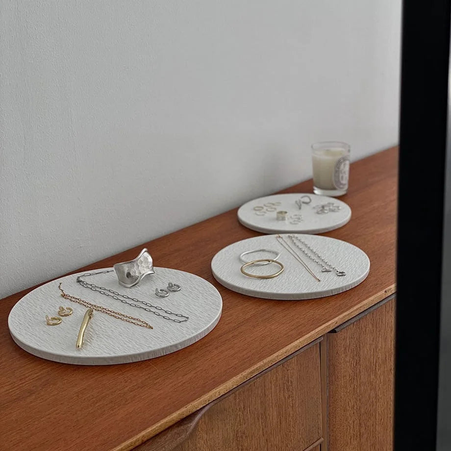 Angled shot of three textured ceramic jewelry organizers with various rings, necklaces, and earrings. - RoomDen