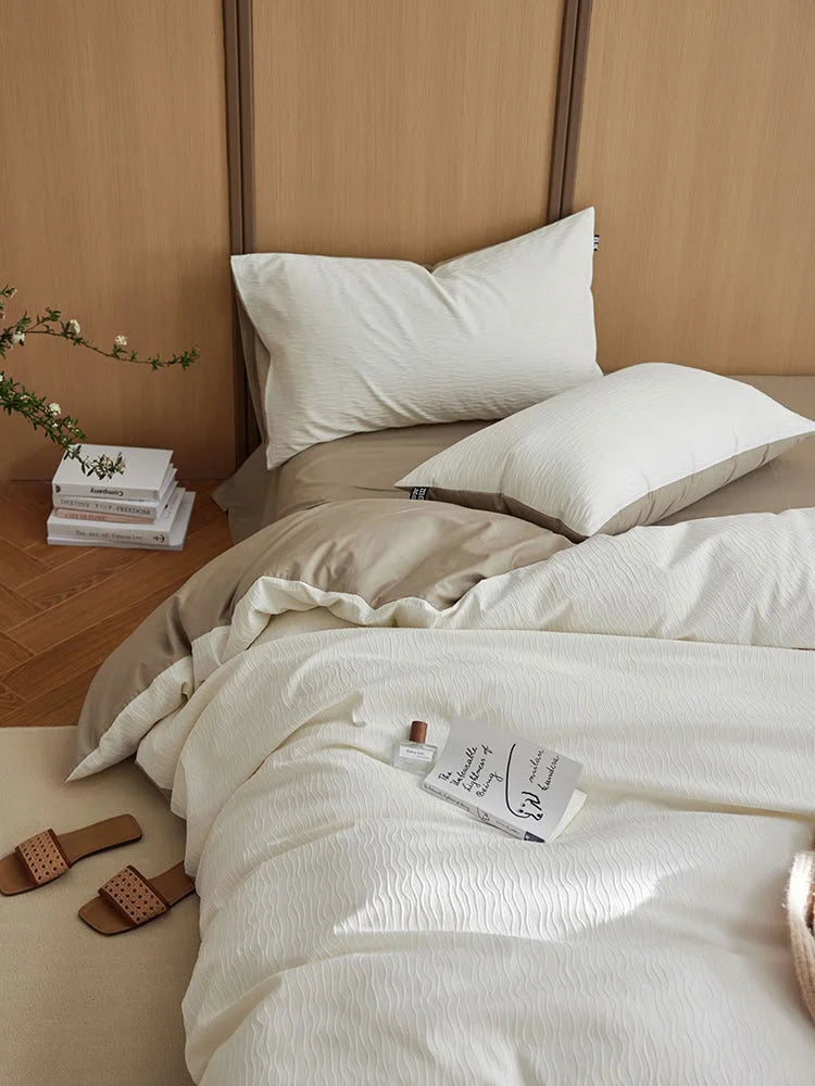 Detail shot of the Cream White wavy texture with a book and perfume bottle on the duvet cover. - RoomDen