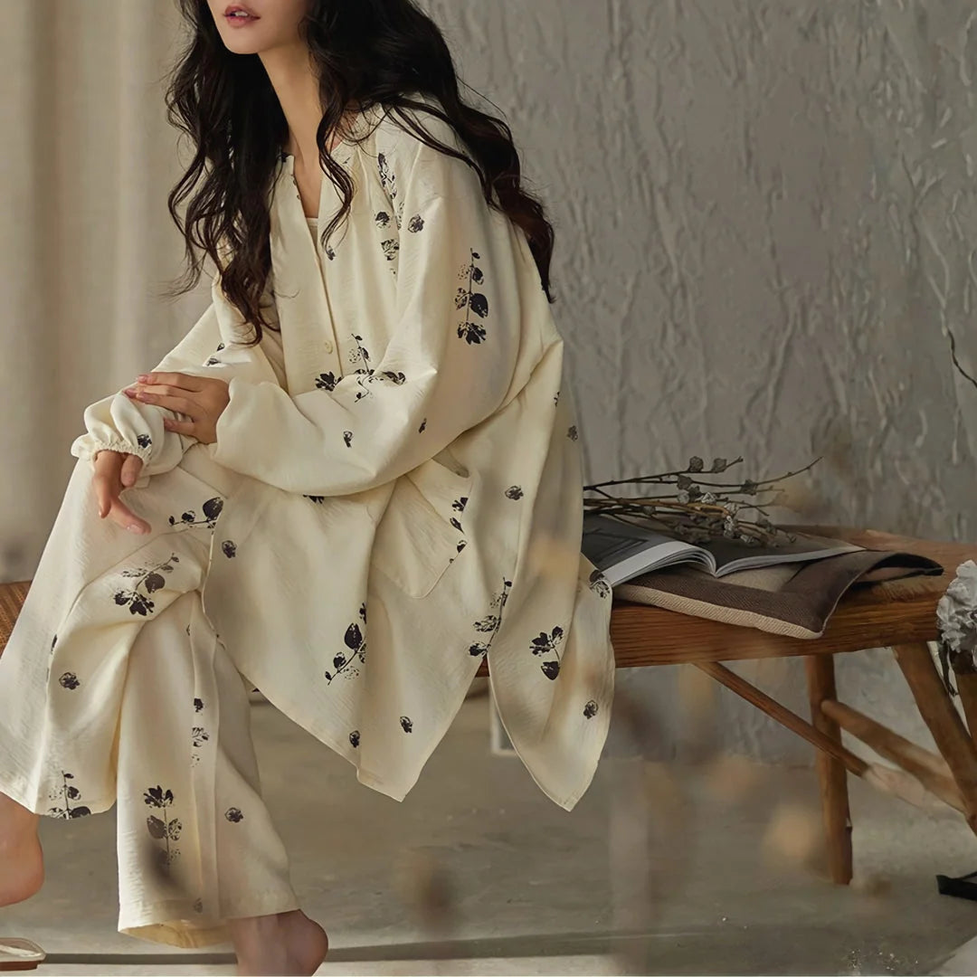 Lightweight Textured Botanical Print Cotton Pajama Set in creamy beige, model sitting on a wooden bench - RoomDen