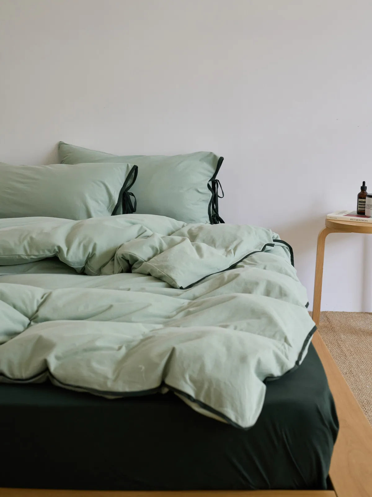 Side angle of the Sage Green & Black bedding set on a wooden bed frame, highlighting its cozy feel. - RoomDen