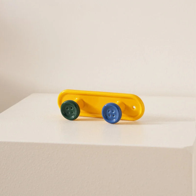 Yellow 2-hook button ceramic wall rack with green and blue buttons on a white surface. - RoomDen