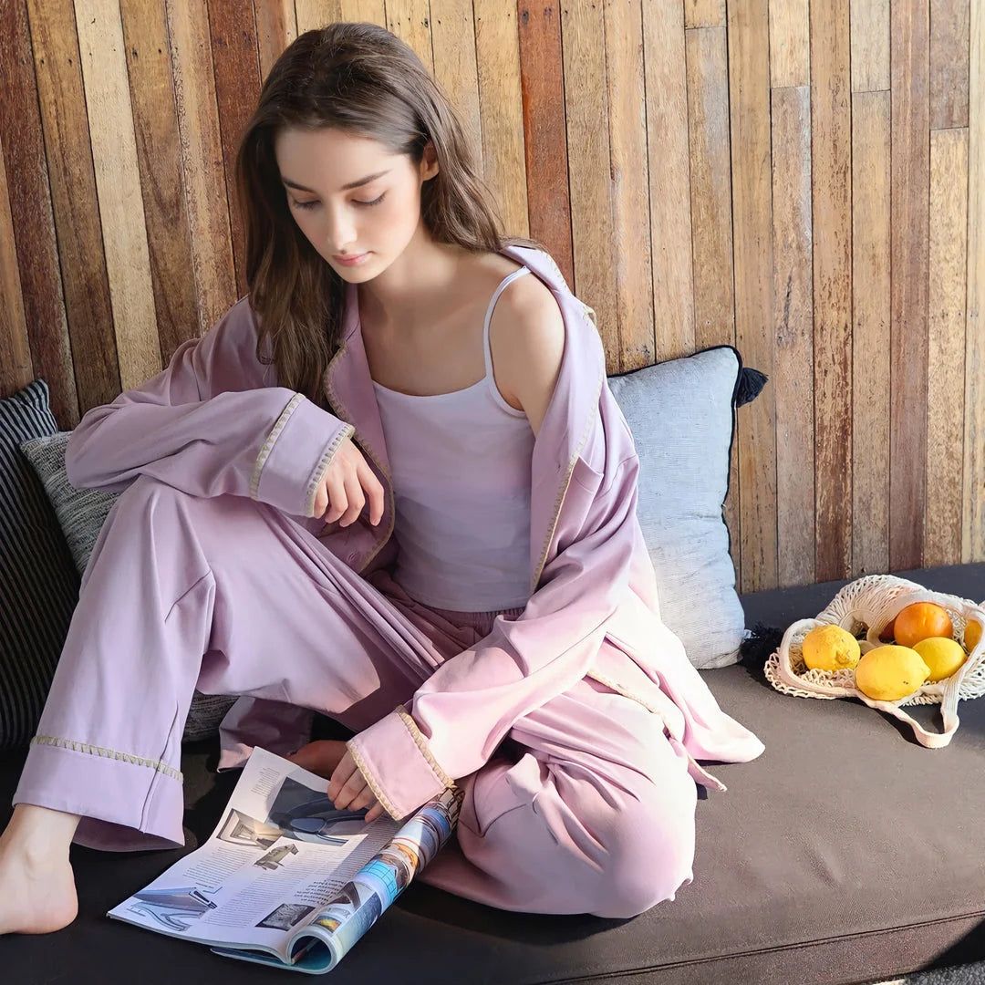 Closer shot of the model sitting on a couch in the lavender pajama set, showcasing the fabric's drape. - RoomDen