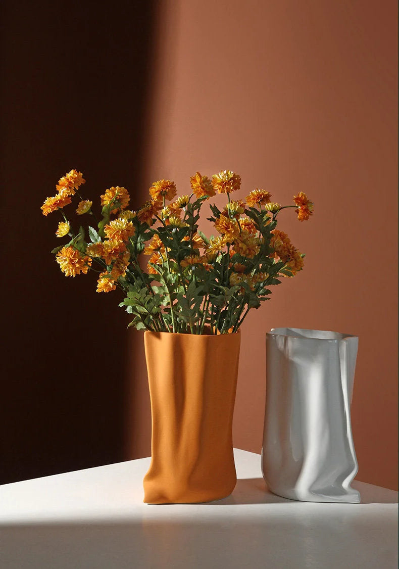 The Tangerine and Cream White paper bag vases styled together on a white surface, showcasing the color contrast and ruched texture - RoomDen.