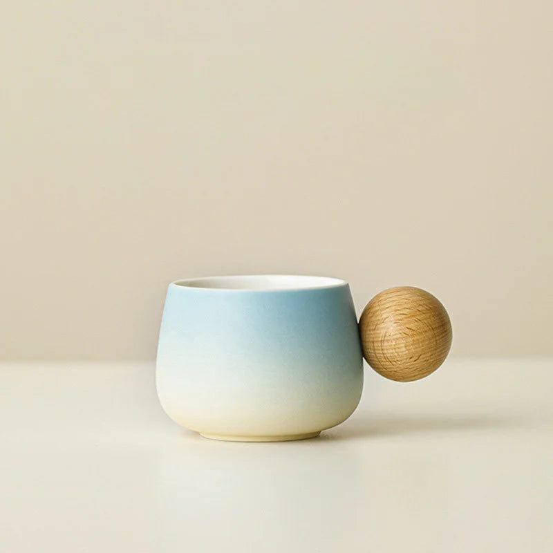 A clear studio shot of the Sky Blue gradient ceramic mug with its spherical wooden handle. - RoomDen