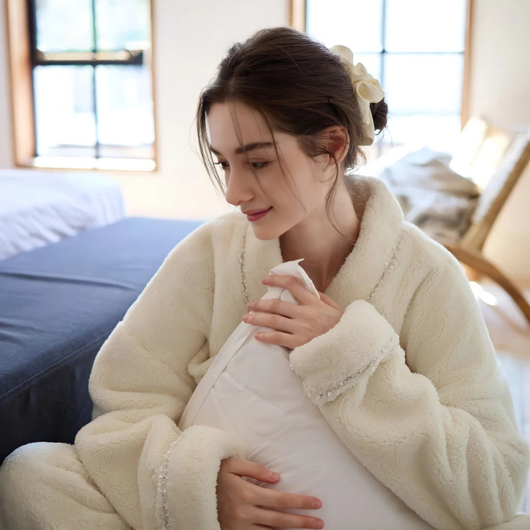Detailed shot of the model's face and the soft collar of the cream fleece pajama top as she holds a pillow - RoomDen.
