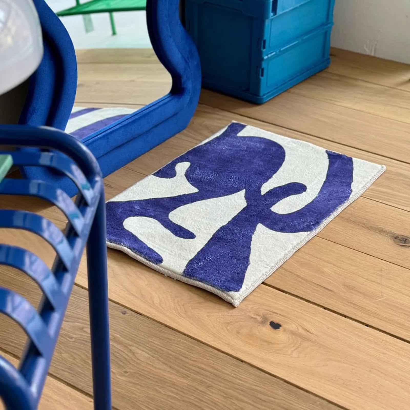 High angle view of the blue and white abstract rug on wooden floor next to blue crates