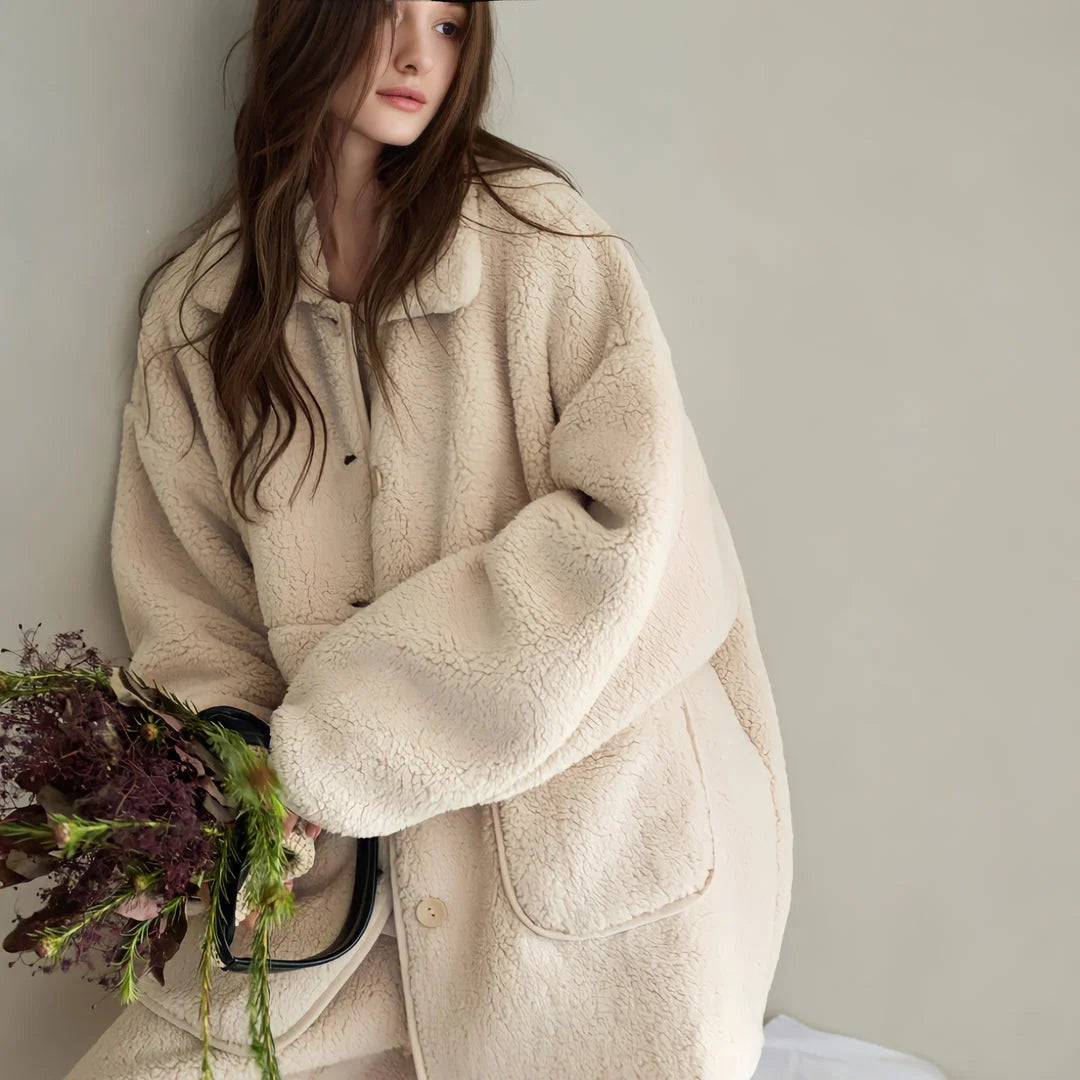 Model leaning against a wall holding a bouquet, wearing the Creamy Beige Fleece Pajama Set.