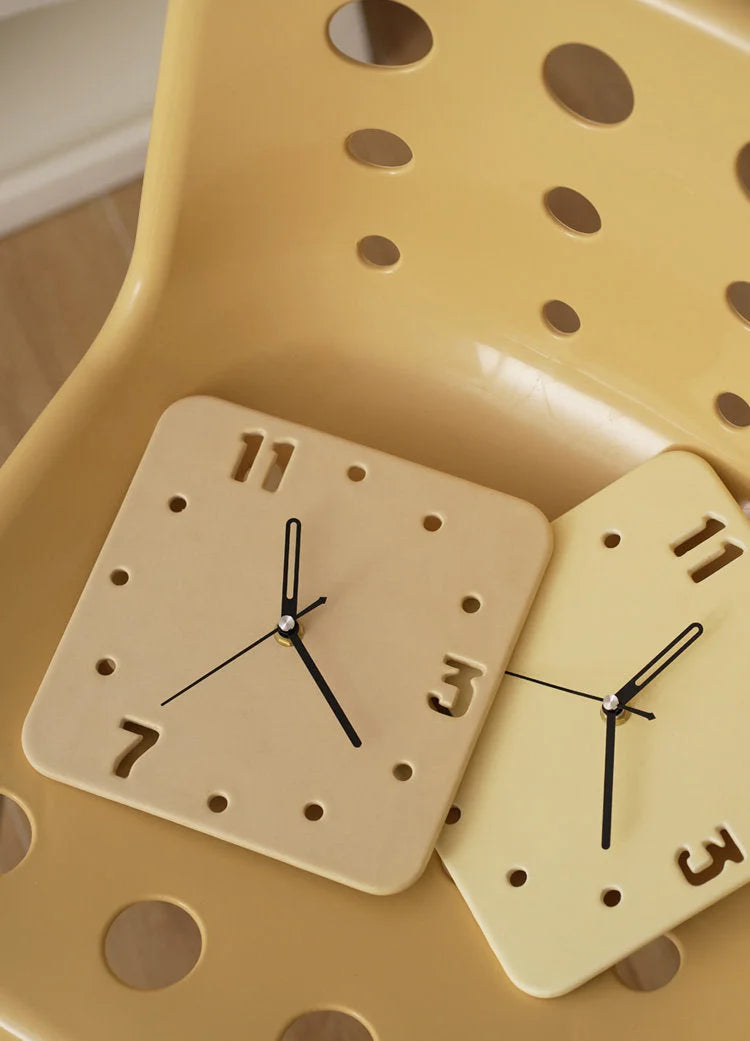 Two Butter Yellow ceramic clocks resting on a matching perforated chair, showing their versatile placement - RoomDen.